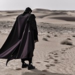 یک مرد  اسرارآمیز با شنل چشمگیر که در صحرا قدم می زند