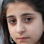 یک دختر نوجوان ایرانی تبار با چشمان قهوه ای بدون روسری، به حالت عمیق به دوربین خیره شده است.