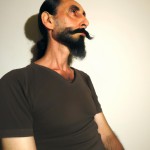 مردی ایرانی با موهای مشکی بلند و از پشت بسته شده، با دماغی عقابی و ریش و سبیل پرپشت