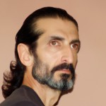 مردی ایرانی با موهای مشکی بلند و از پشت بسته شده، با دماغی عقابی و ریش و سبیل پرپشت