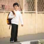 پسربچه ایرانی دبستانی در راه مدرسه با لباس فرم مدرسه