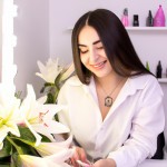 یک ناخنکار رویایی زیبا با موهای بلند مشکی در سالن زیبایی که پر از گل های نیلوفر در حال کار کردن است