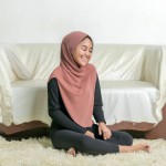 دختر زیبا با حجاب و موهای بلند نشسته بر روی قالیچه  سلیمان