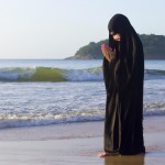 یه دختر با چادر که داره تو ساحل دریا نماز می خونه