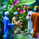 امام زمان در حال نگاه کردن به یاران خود که دورش حلقه زده‌اند در یک باغ سبز و پر از گلهای رنگارنگ