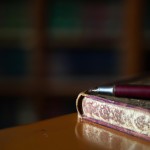 یک کتاب در کنار یک قلم نی که در یک کتابخانه قدیمی است
