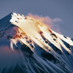 A snowy mountain peak at dawn, captured in early dawn's first light, free of man-made structures and void of animal figures, emphasizing the pristine beauty of the natural environment.