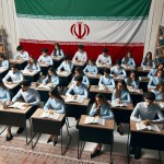 بیست دانش آموز ایرانی که کلاس نهم هستند و در کلاس مطالعات اجتماعی هستند و پیراهن سورمه ای و شلوار مشکی پوشیدن و خیلی خوش تیپ هستند و فضای کلاس هم خیلی زیباست و پرچم ایران پشت سرشون هست.