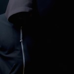 یک پروفایل میخام با بک گراند مشکی از مردی که هودی مشکی پوشیده و رو به دوربین صاف ایستاده و کلاه هودی را روی سرش انداخته و چهرش مشخص نیست