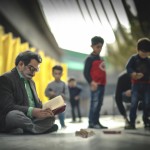 استاد شهریار شاعر در کنار میدان آزادی تهران در بین کودکان در حال خواندن کتاب شعر