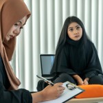 دختری محجبه و غمگین که در اتاق مشاوره   کنار مشاور خانم نشسته است