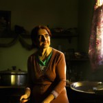 A Resilient Woman: Illustrate a determined woman  of old iran standing in a modest kitchen, looking hopeful as she prepares a meal. Sunlight filters through the window, casting a warm glow over her face.