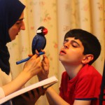 یه بچه که داره پرنده اش بازی می کند وتو خانه هستند و مامانش داره میگه امیرحسین درسات مانده