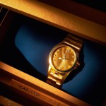 "A cinematic close-up shot of a luxurious gold watch, captured in stunning 4K resolution. The camera focuses on the intricate details of the gold case, with soft light reflecting off its polished surface. The light dances across the curves of the watch, highlighting the craftsmanship and warmth of the gold. Featured model: Rolex Day-Date in yellow gold, known for its classic elegance and smooth finish. The watch's dial and hands catch the light, adding to its opulent look. The background remains