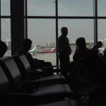 تصویر داخل سالن فرودگاه امام خمینی، انتظار مسافران برای پرواز به همراه پس زمینه ای از پرواز هواپیما ها از پشت شیشه سالن انتظاز