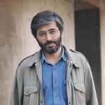 شهید سید مرتض آوینی با پیراهن آبی لی / موی کمی سپید / پیراهن تا کمر دیده شود / اورکت قدیمی کره ای زمان جنگ روی پیراهن بپوشد صورت و کله کاملا دیده شود / لبخند خیلی کم و ملیح ملیح بزند