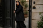 یک زن ۴۵ ساله رو طراحی کن که پوست تیره داره روسری گذاشته و روپوش شلوار گشاده مشکی پوشیده ، صورت خشنی داره و کلید انداخته داره وارد در حیاط منزلش میشه