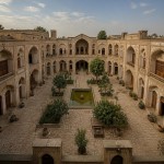 تصویری از یک حیاط بزرگ باستانی که خانه های متعددی در چهار ضلع آن وجود دارد